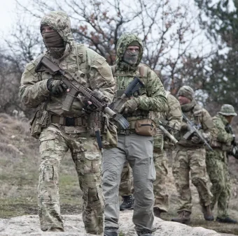 Security team conducting patrol in rural terrain with tactical equipment