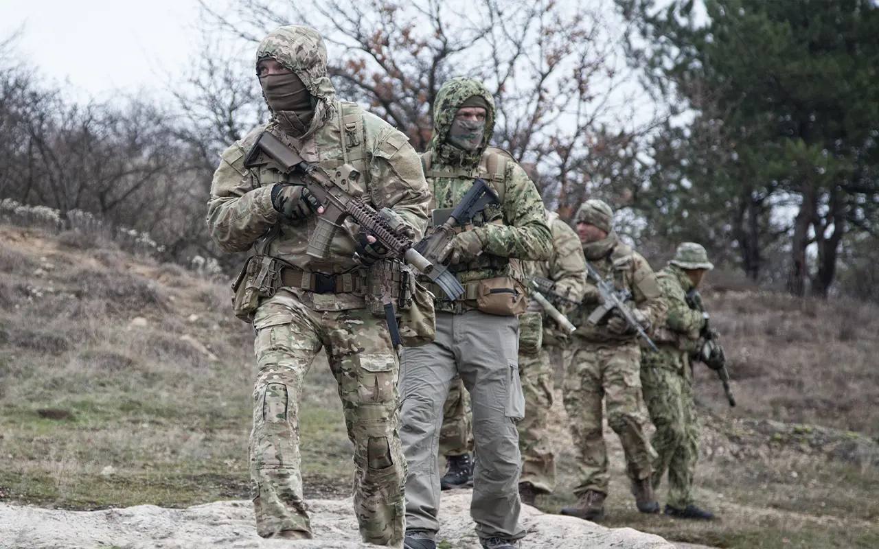 Security team conducting patrol in rural terrain with tactical equipment