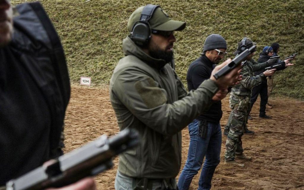 Participants performing structured pistol training on a professional shooting range