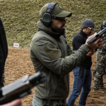 Participants performing structured pistol training on a professional shooting range